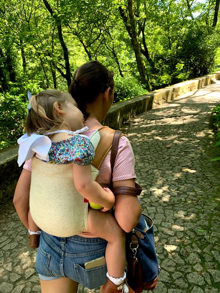 Summer wearing her daughter in an Onbuhimo carrier on a cobbled path in Sintra
