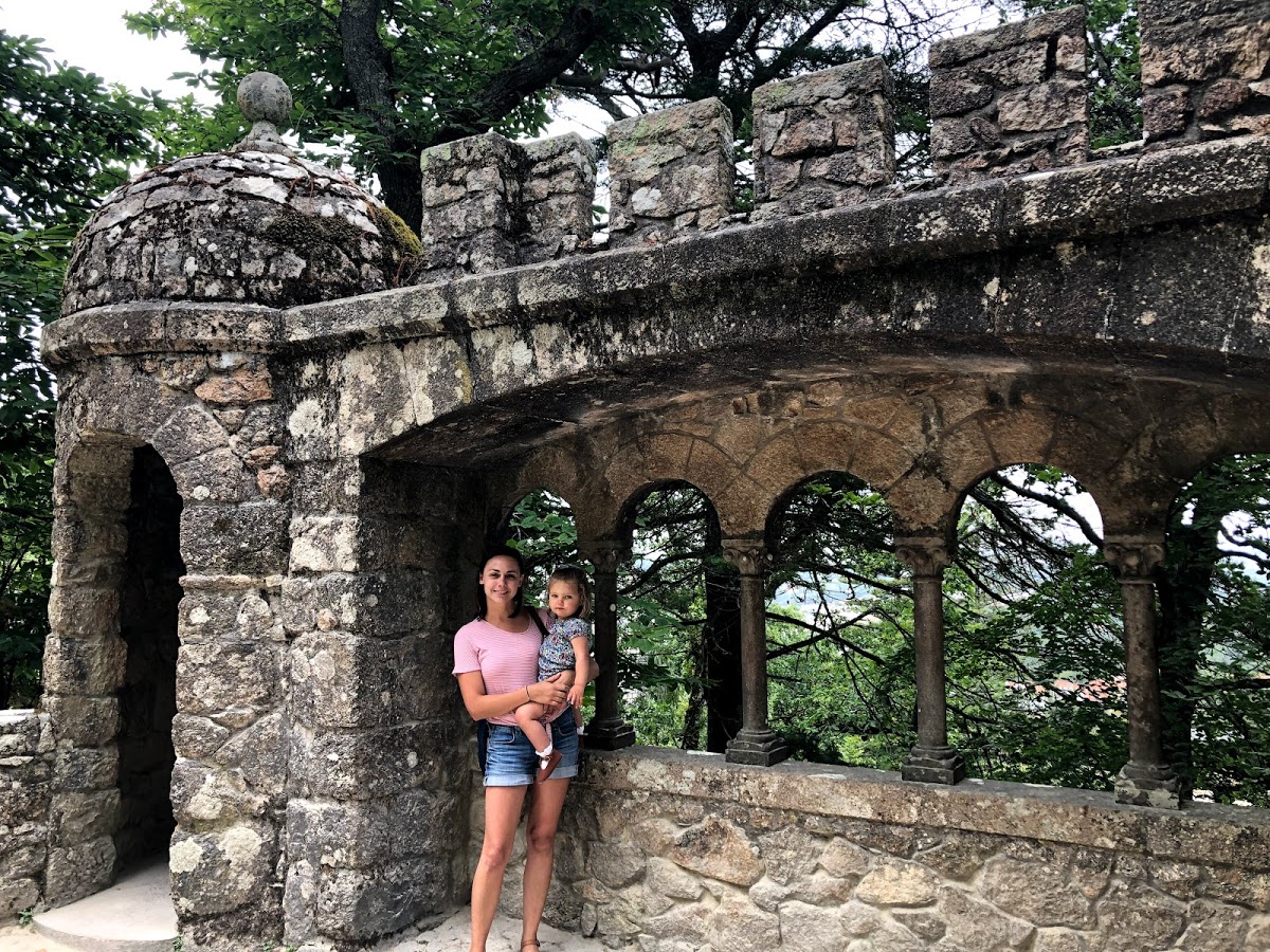 Summer holding her daughter under stone arches at Quinta da Regaleira