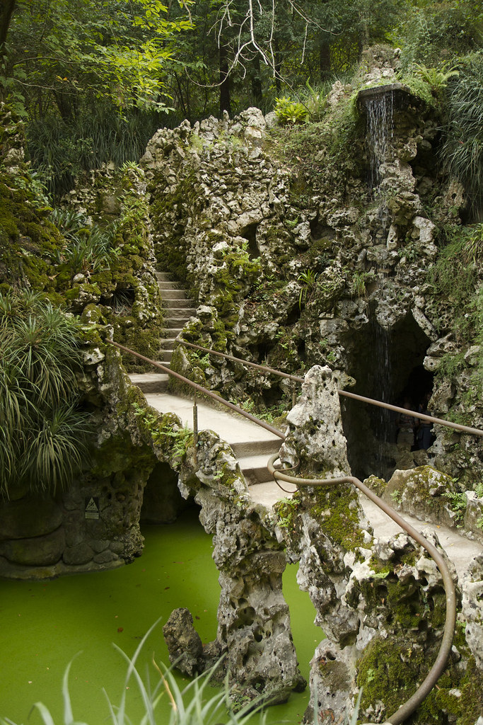 Stone bridge and grotto over the green lake at Quinta da Regaleira