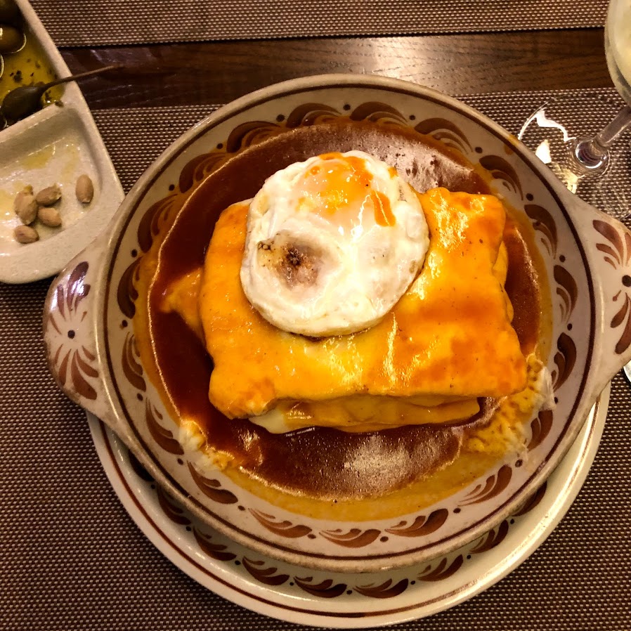 Francesinha, Porto's famous sandwich, topped with a fried egg and sauce