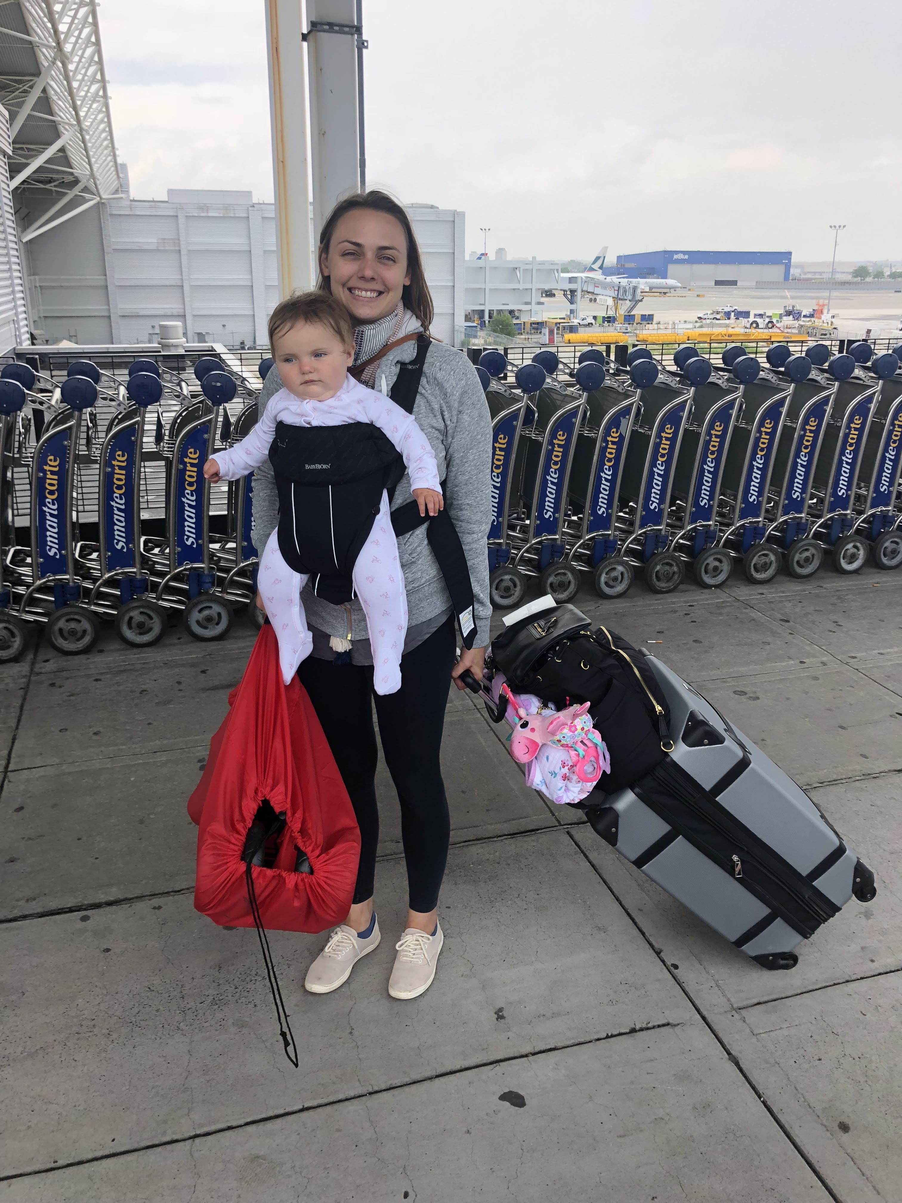 Summer at the airport with her baby in a carrier and luggage