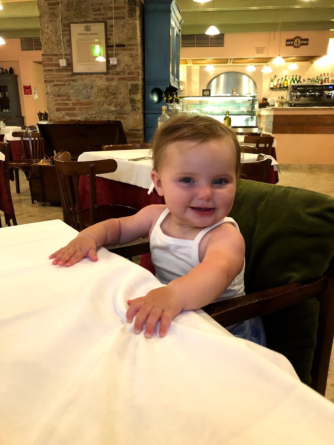 Baby smiling at the table at Trattoria da Ubaldo in Lucca