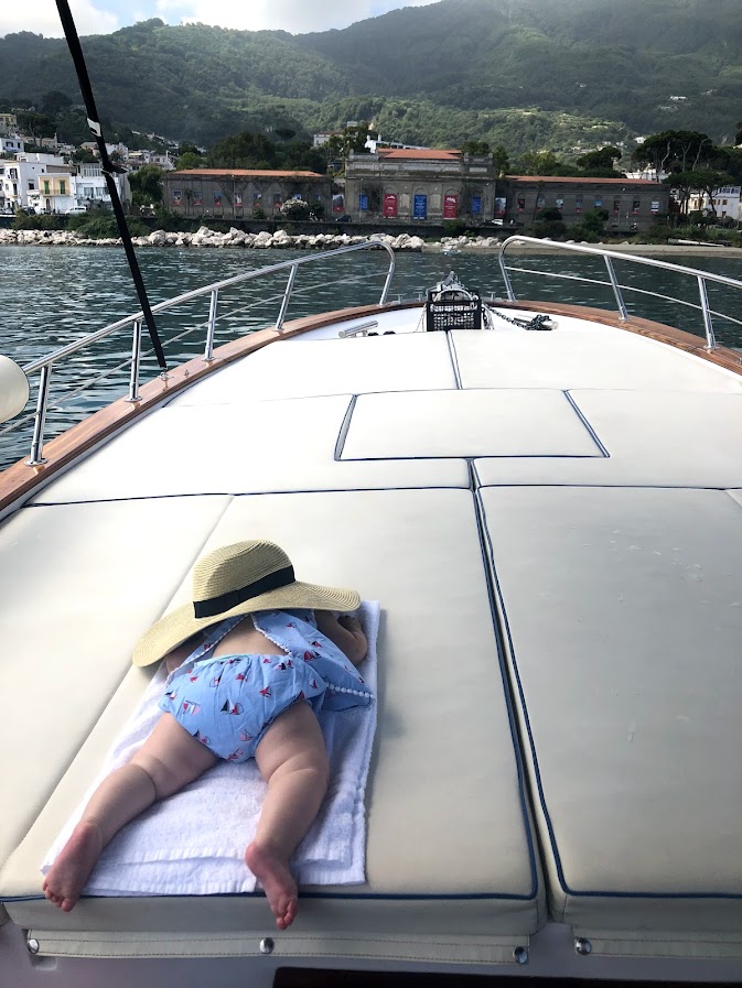 Baby napping on a towel on the deck of a boat in Ischia