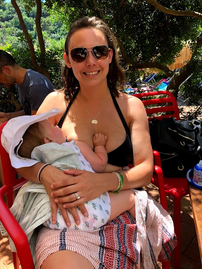 Summer holding her baby at lunch by the sea in Italy