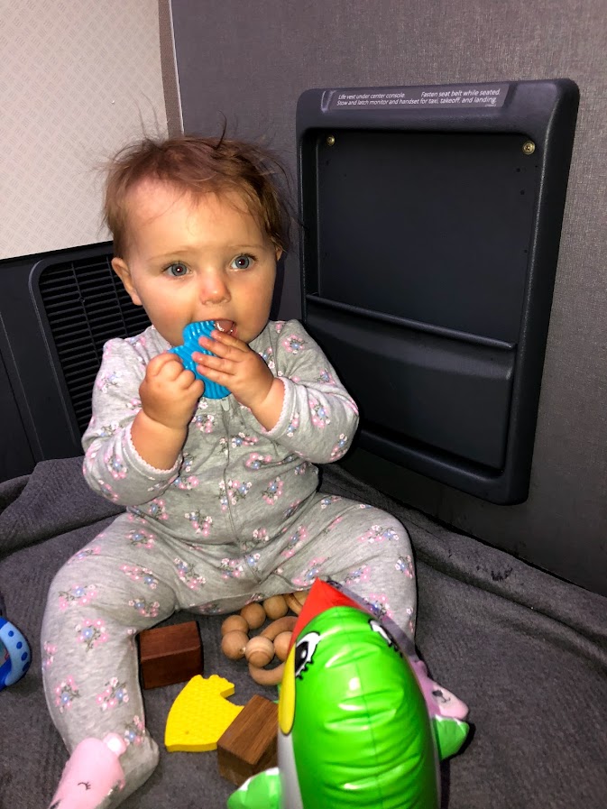 Baby playing with toys on the bulkhead floor of the plane