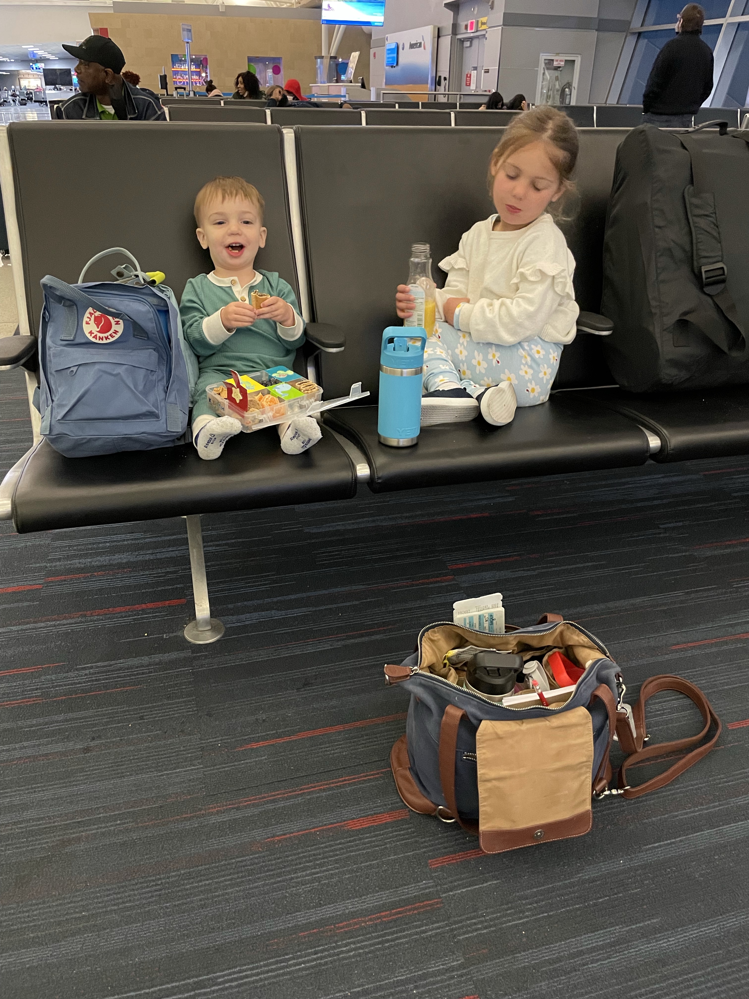 Summer's two kids waiting at the airport gate with snacks