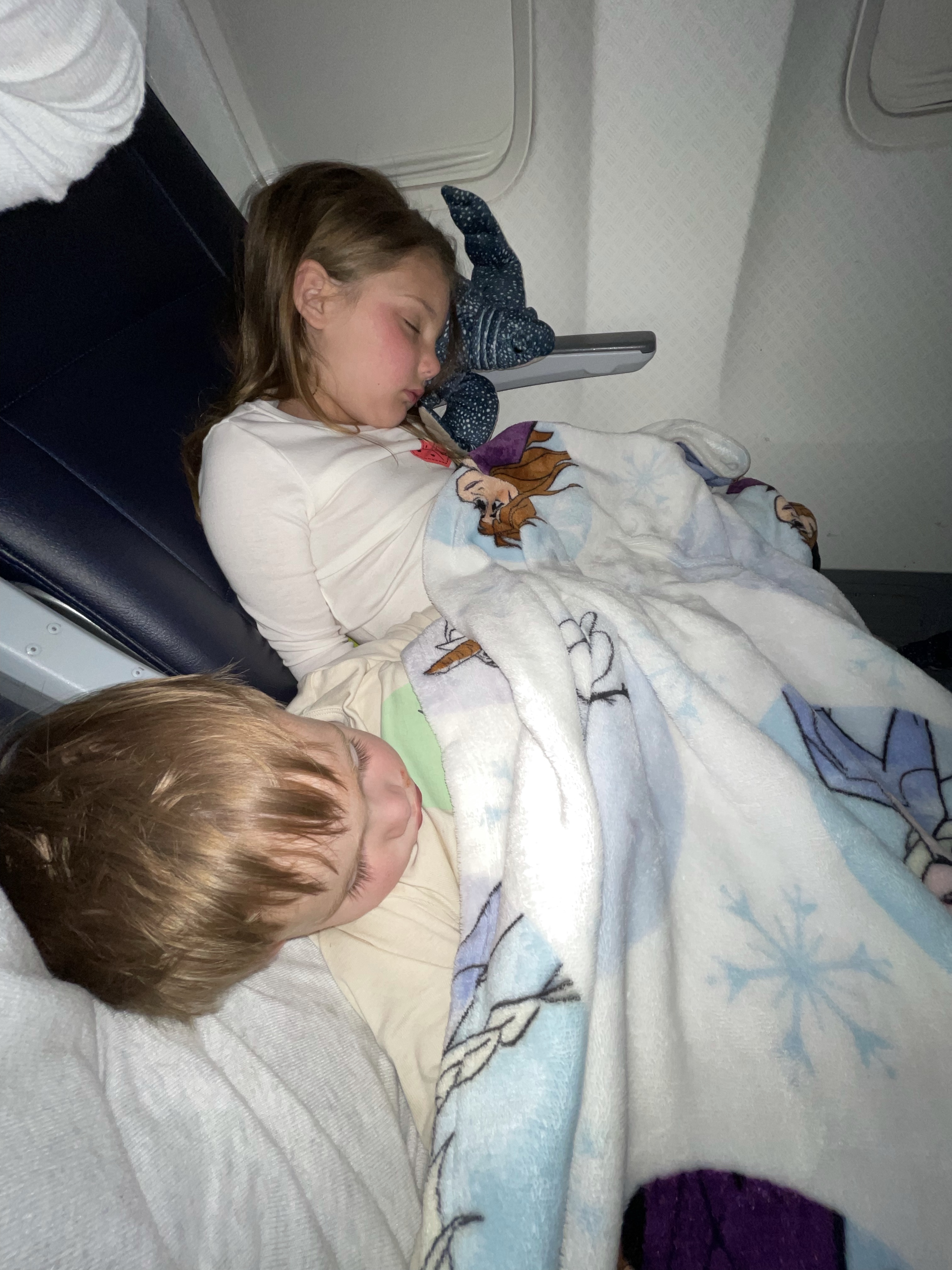 Summer's kids asleep under a blanket on the plane