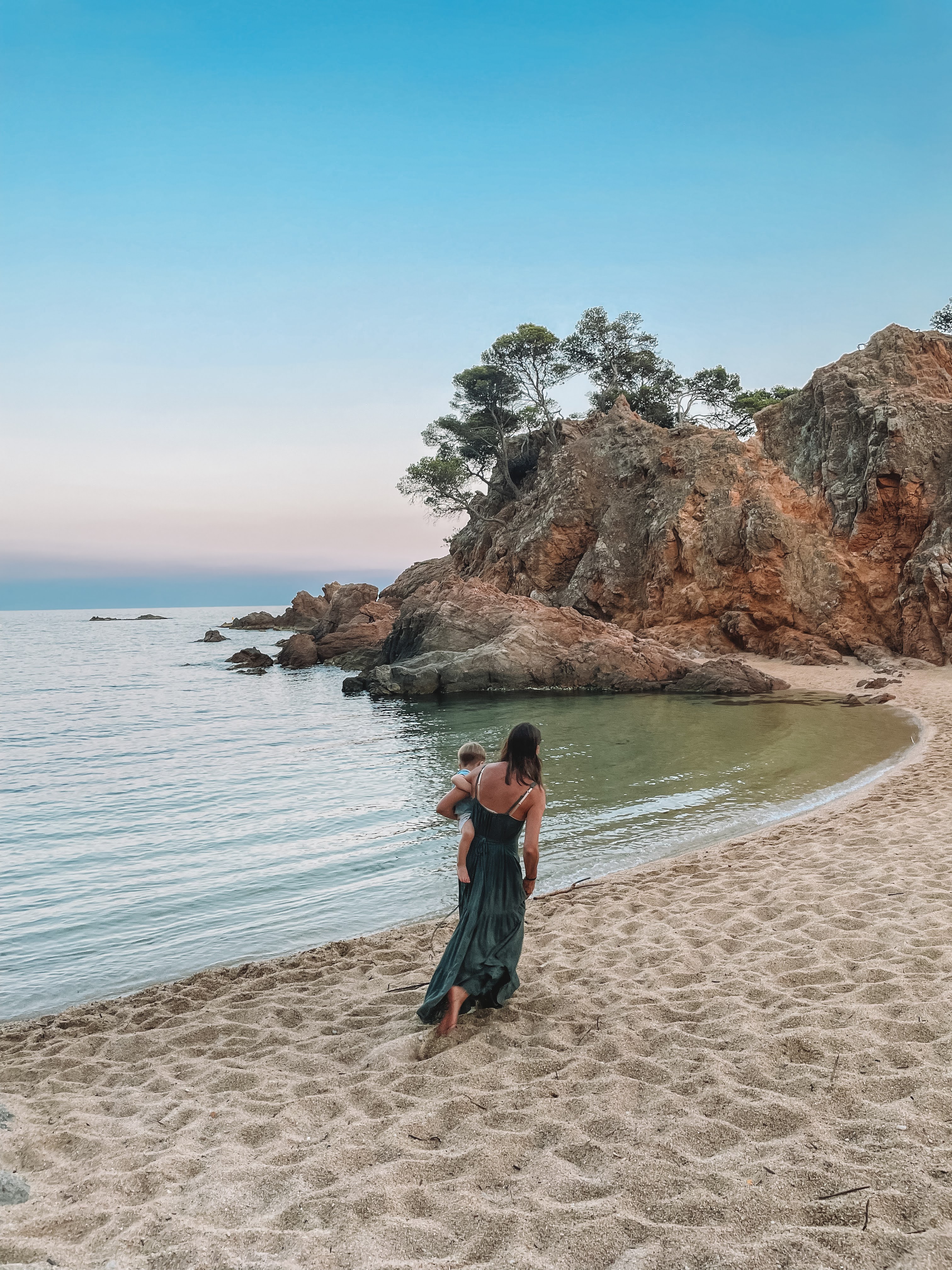 Summer carrying her son along the beach at sunset near Platja d'Aro