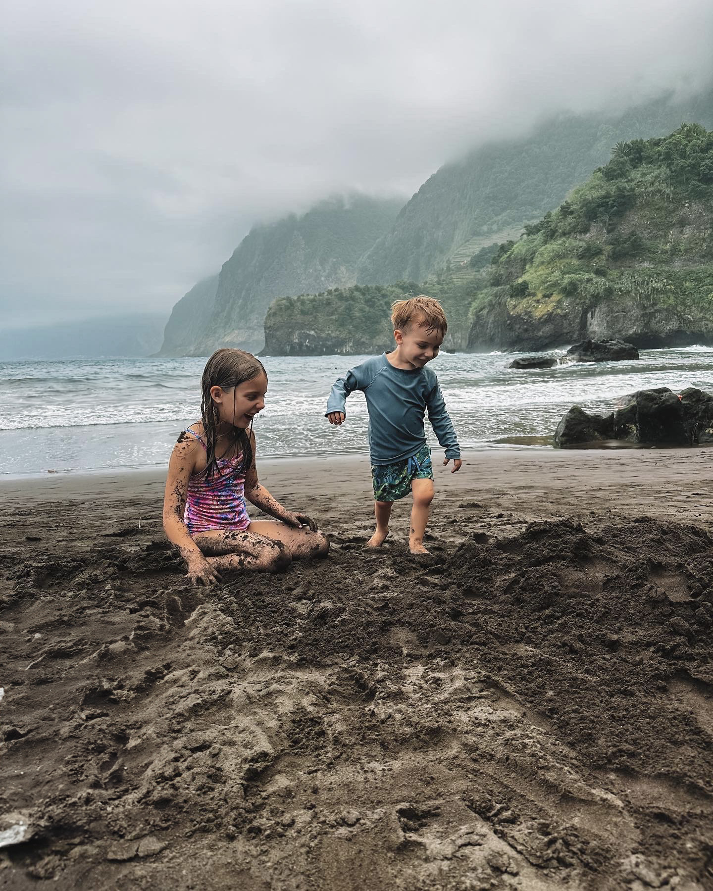 Summer's kids playing in black sand on a beach in Madeira