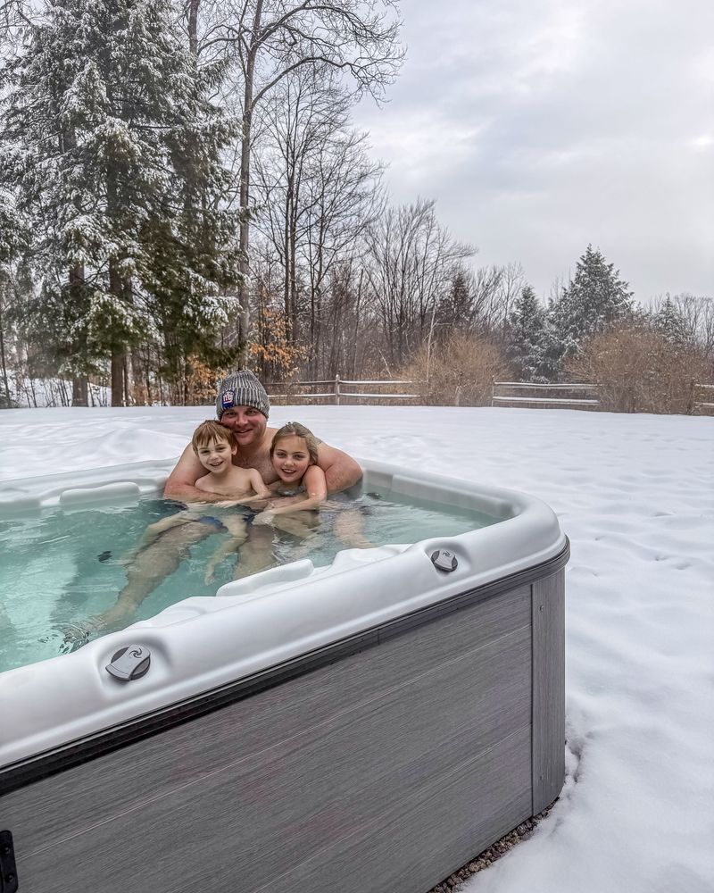 A family in an outdoor hot tub surrounded by snow