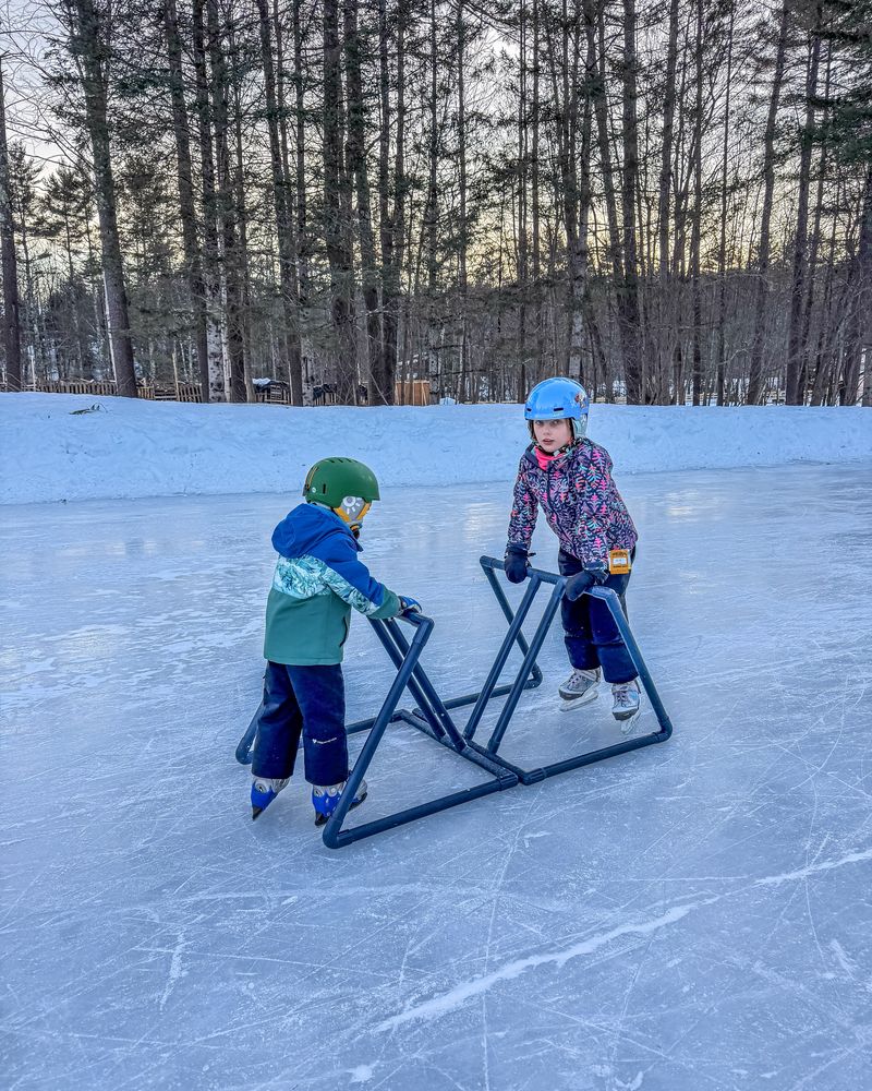 Two kids skating with skate aids on an outdoor pond in Jackson