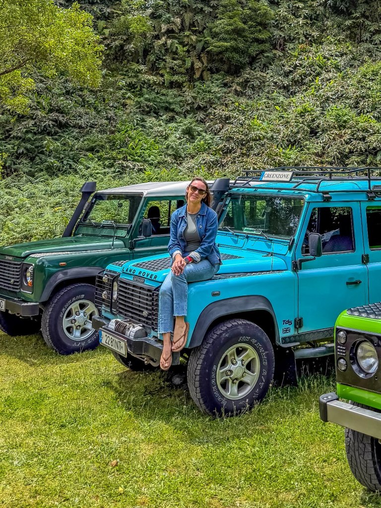 Summer Romeo, founder of Out Making Memories, sitting on a 4x4 jeep surrounded by green forest on São Miguel, the Azores
